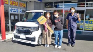 白色の新車N-BOXカスタムターボの御納車写真。N様ご夫妻に担当の小笠原を添えて。