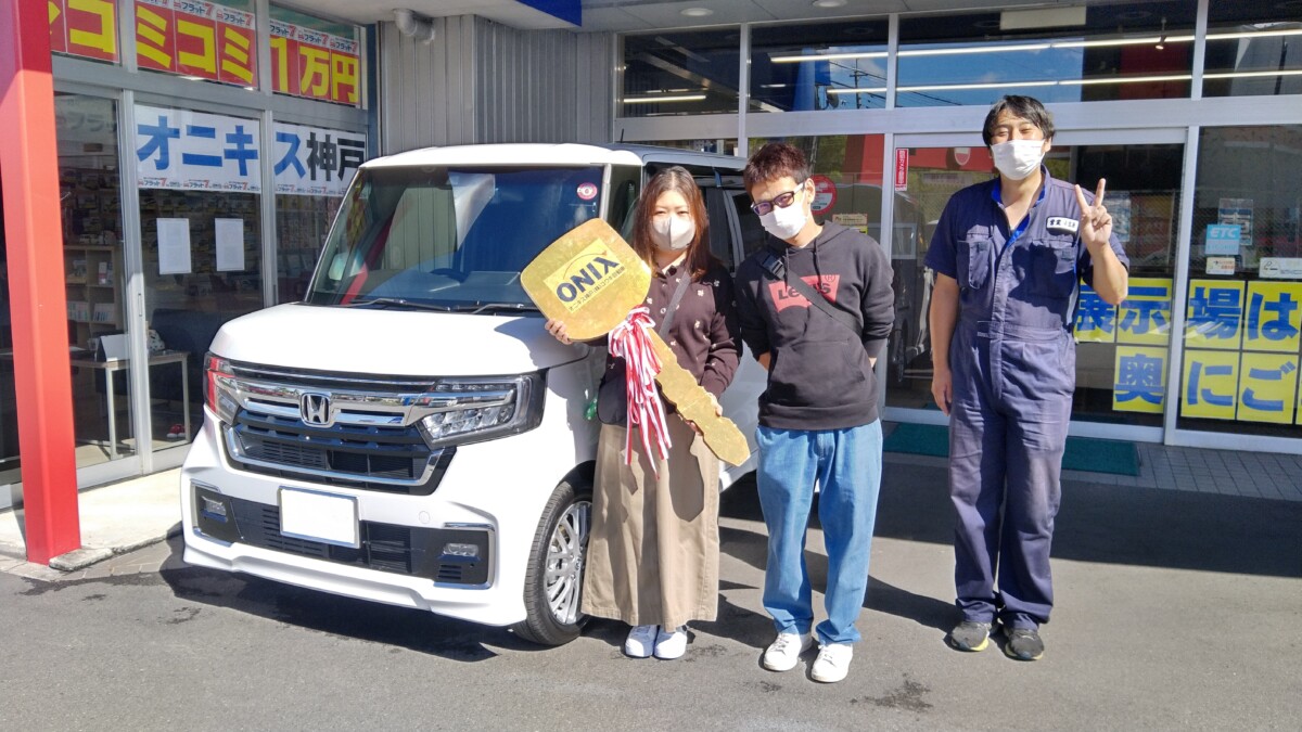 白色の新車N-BOXカスタムターボの御納車写真。N様ご夫妻に担当の小笠原を添えて。